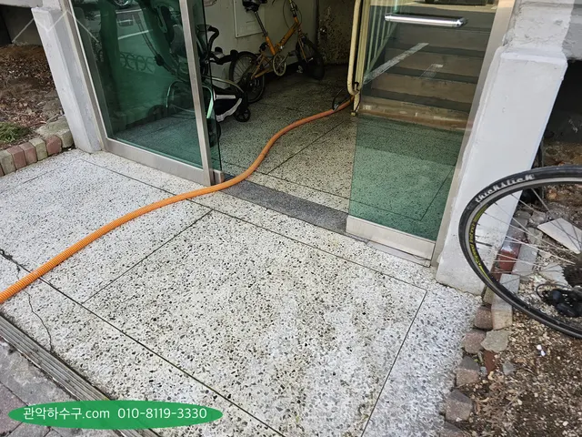건물 현관 안쪽 계단까지 이어진 주황색 고압세척 호스